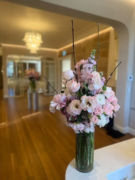 Corporate pedestal flowers: pale pink and white arrangement in a hallway with a chandelier