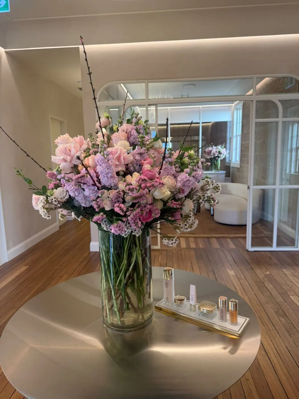 Luxury retail flower arrangement in Sydney: blush, lilac and white blooms with cherry blossom on a mirrored table