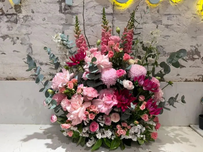 Corporate gift flowers: low pink arrangement of roses, dahlias, ranunculus and eucalyptus