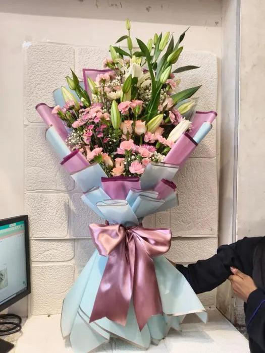 Corporate presentation bouquet of pink lilies, roses and carnations wrapped with a satin bow