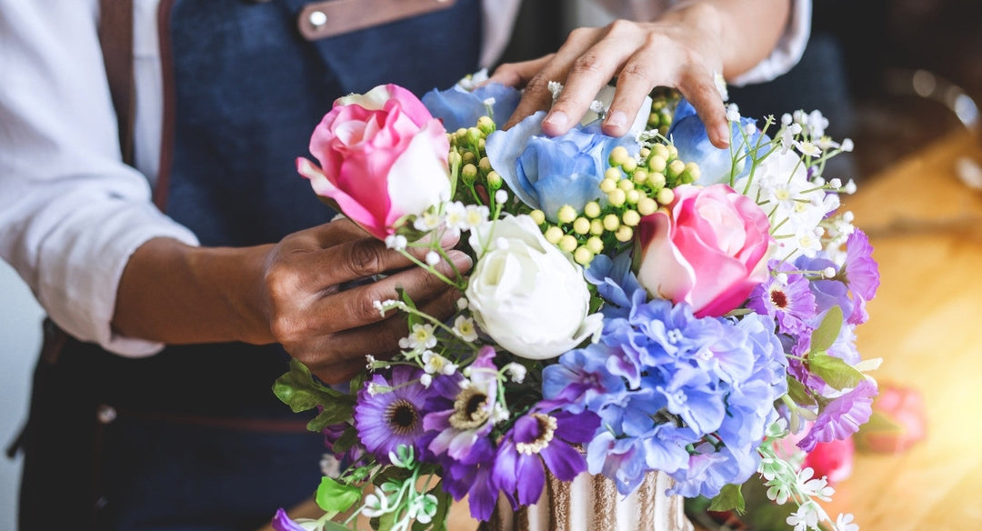 A Vhouse florist arranging pink, blue and white flowers with greenery