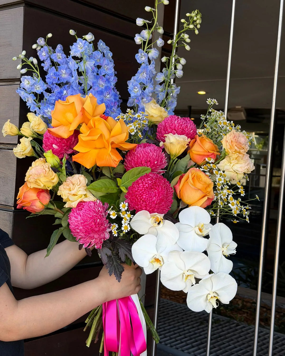 Spring flower bouquet with orange roses, blue delphiniums, pink chrysanthemums and white orchids by Vhouse Florist Sydney