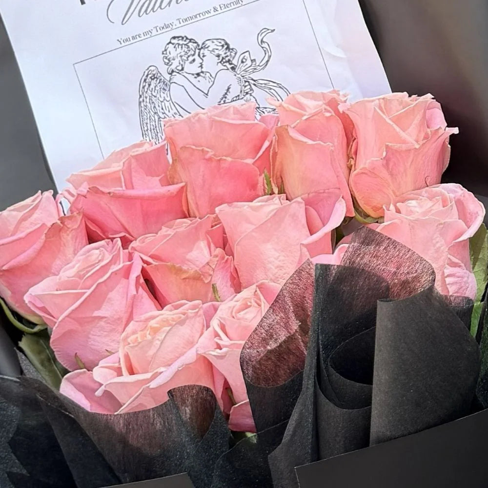 Close-up of 12 blush pink roses bouquet in black paper with romantic cupid gift card, Sydney same-day luxury pink rose delivery by Vhouse Florist