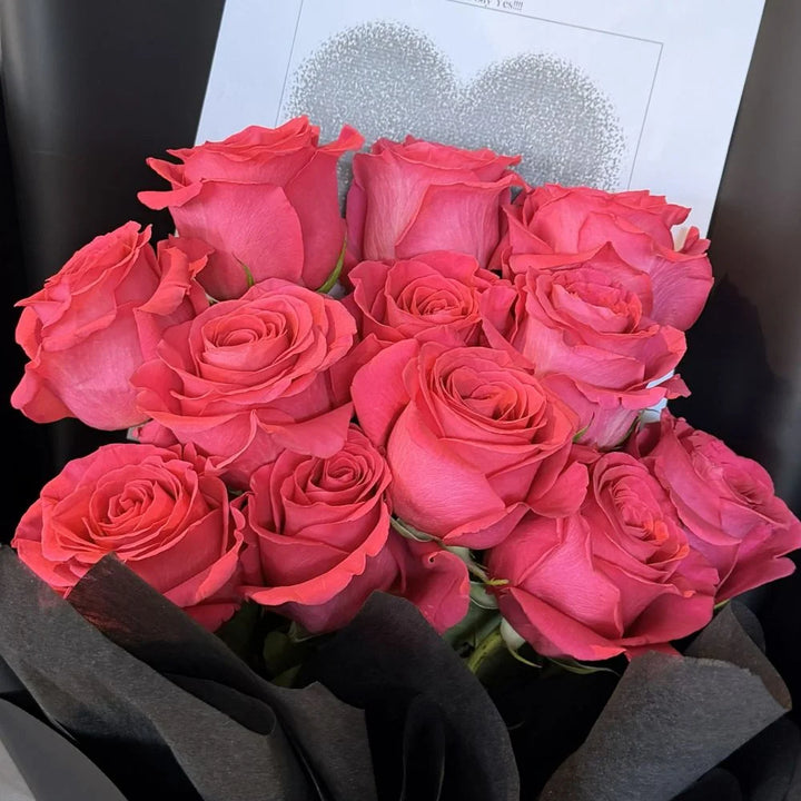 Close-up of 12 hot pink roses bouquet in black paper with romantic heart gift card, Sydney same-day luxury hot pink rose delivery by Vhouse Florist