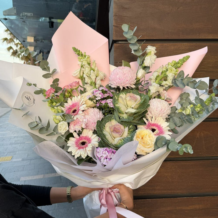 Luxury pink bouquet with gerberas, ornamental kale, pink chrysanthemums, snapdragons and eucalyptus held outdoors, Sydney same-day luxury flower delivery by Vhouse Florist