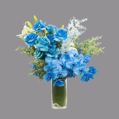 Blue flowers with greenery in cylindrical glass vase from Vhouse Florist