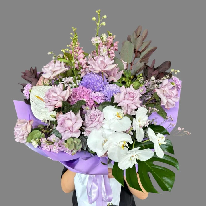 Amethyst Love luxury bouquet with lavender roses, white orchids, blue chrysanthemums, pink snapdragons and monstera leaves in purple wrap, Sydney luxury flower delivery by Vhouse Florist