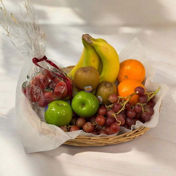 Assorted fruit basket of oranges, green apples, red grapes, kiwi, strawberries and bananas, tabletop view