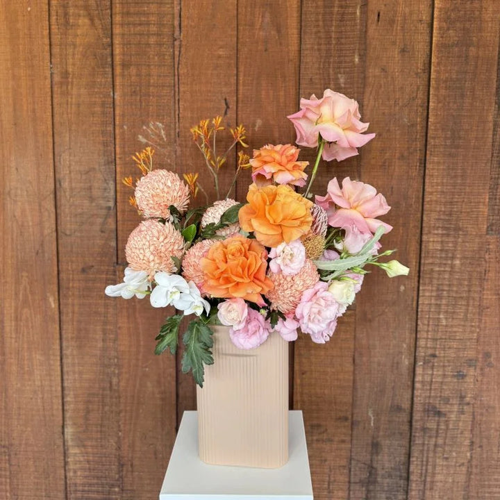 Autumn Blaze - orange, light pink and white flowers in a pastel pink ceramic vase, front view