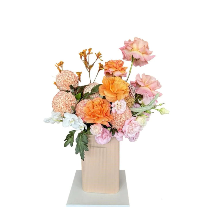 Autumn Blaze - orange, light pink and white flowers in a pastel pink ceramic vase, front view