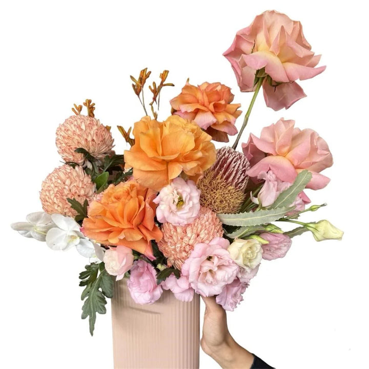 Autumn Blaze - orange, light pink and white flowers in a pastel pink ceramic vase, hand-held view
