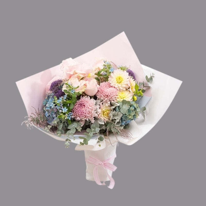 Luxury bouquet of hydrangea, soft pink roses, dusty miller, ast foliage, and texture in paper wrap.