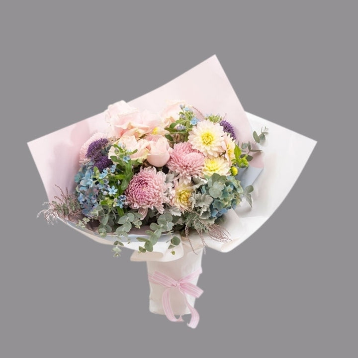 Luxury bouquet of hydrangea, soft pink roses, dusty miller, ast foliage, and texture in paper wrap.