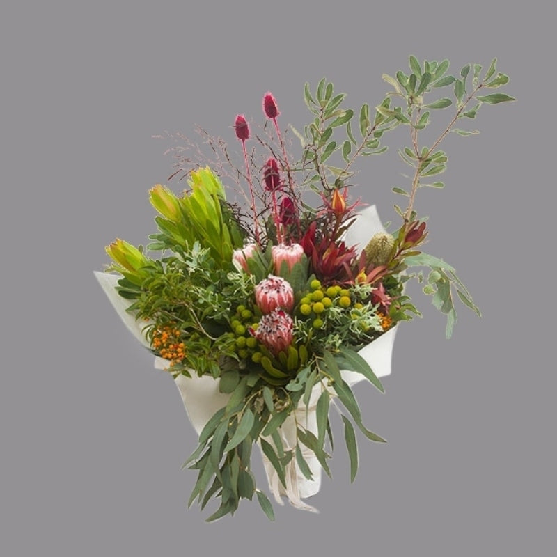Native flowers like proteas, banksias, red thistle, wattle, and gum in paper wrap