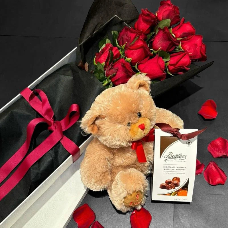Luxury romantic gift set with red roses in black wrap, teddy bear and chocolates on dark background with rose petals, Sydney same-day luxury flower and gift delivery by Vhouse Florist