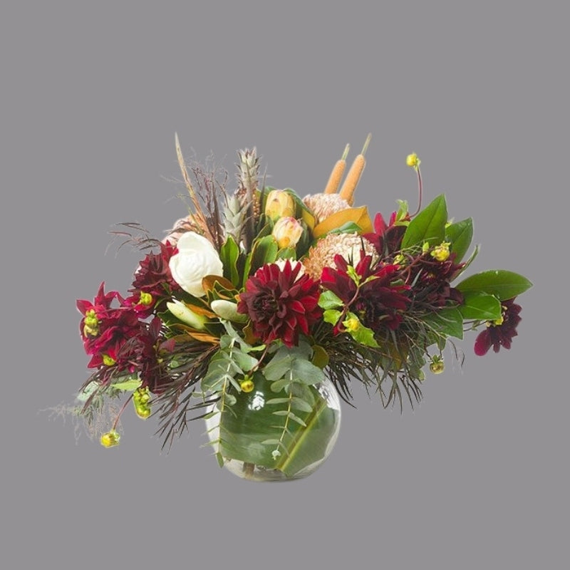 Bright red and light pink fresh flowers in a spherical fish bowl shape glass vase