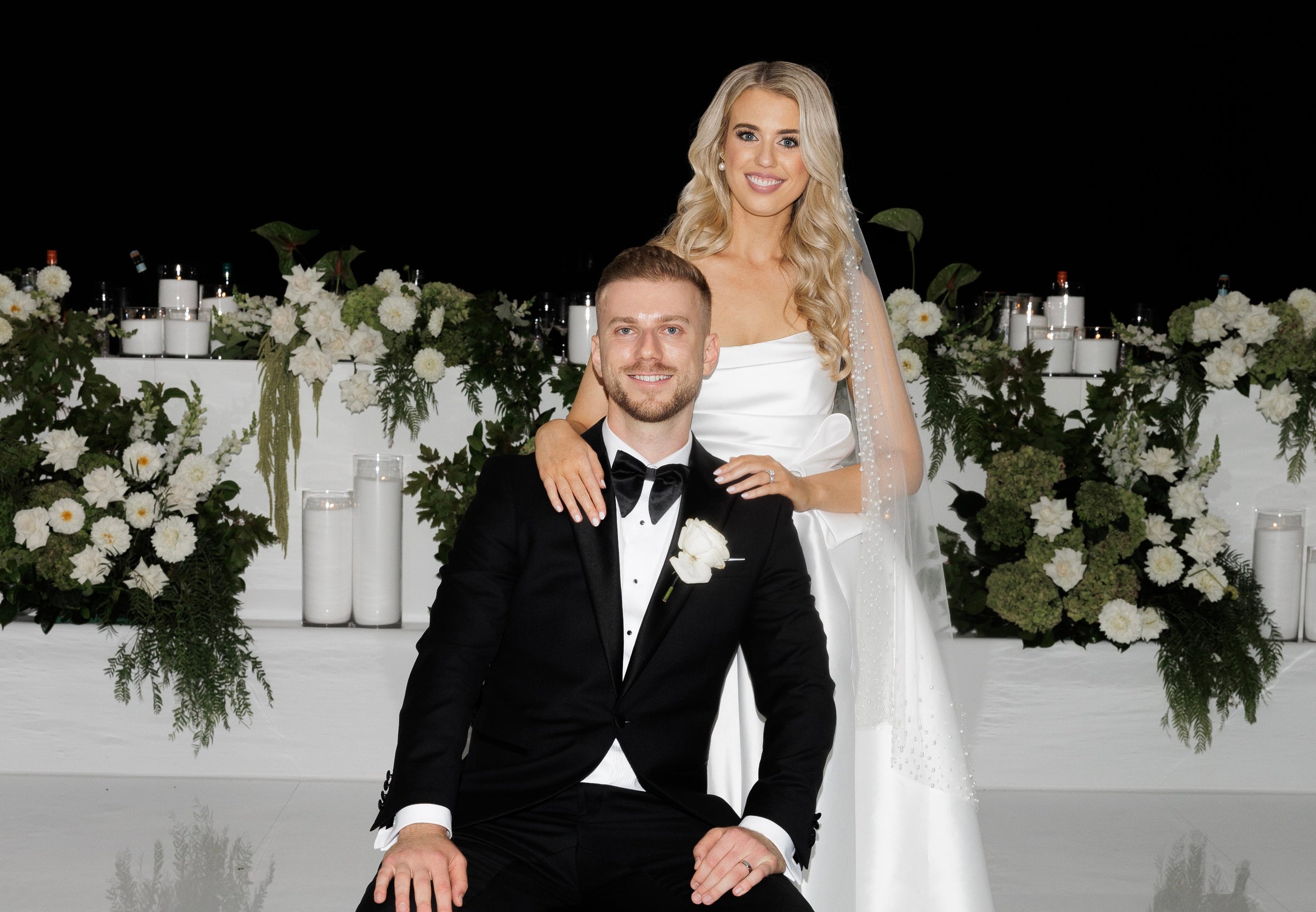 Wedding hero - Groom and Bride with white floral backdrop