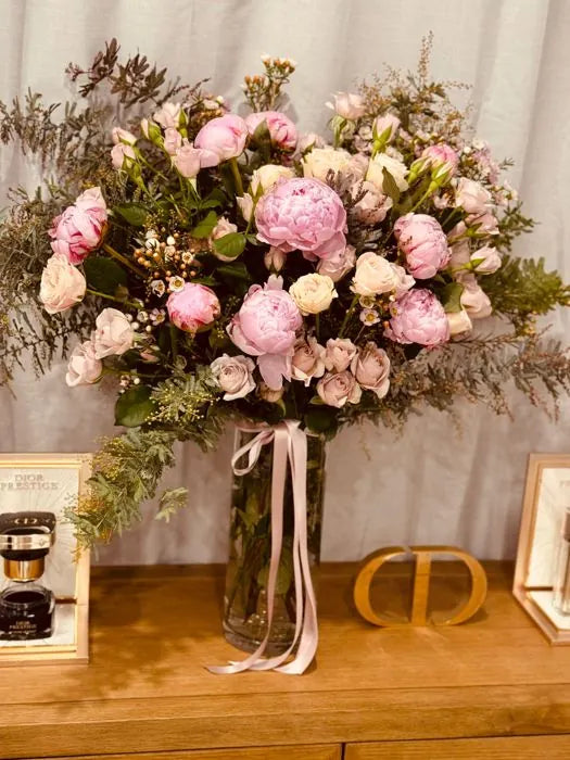 Boutique flower arrangement of pink peonies, roses and native foliage on a timber console in a Dior boutique