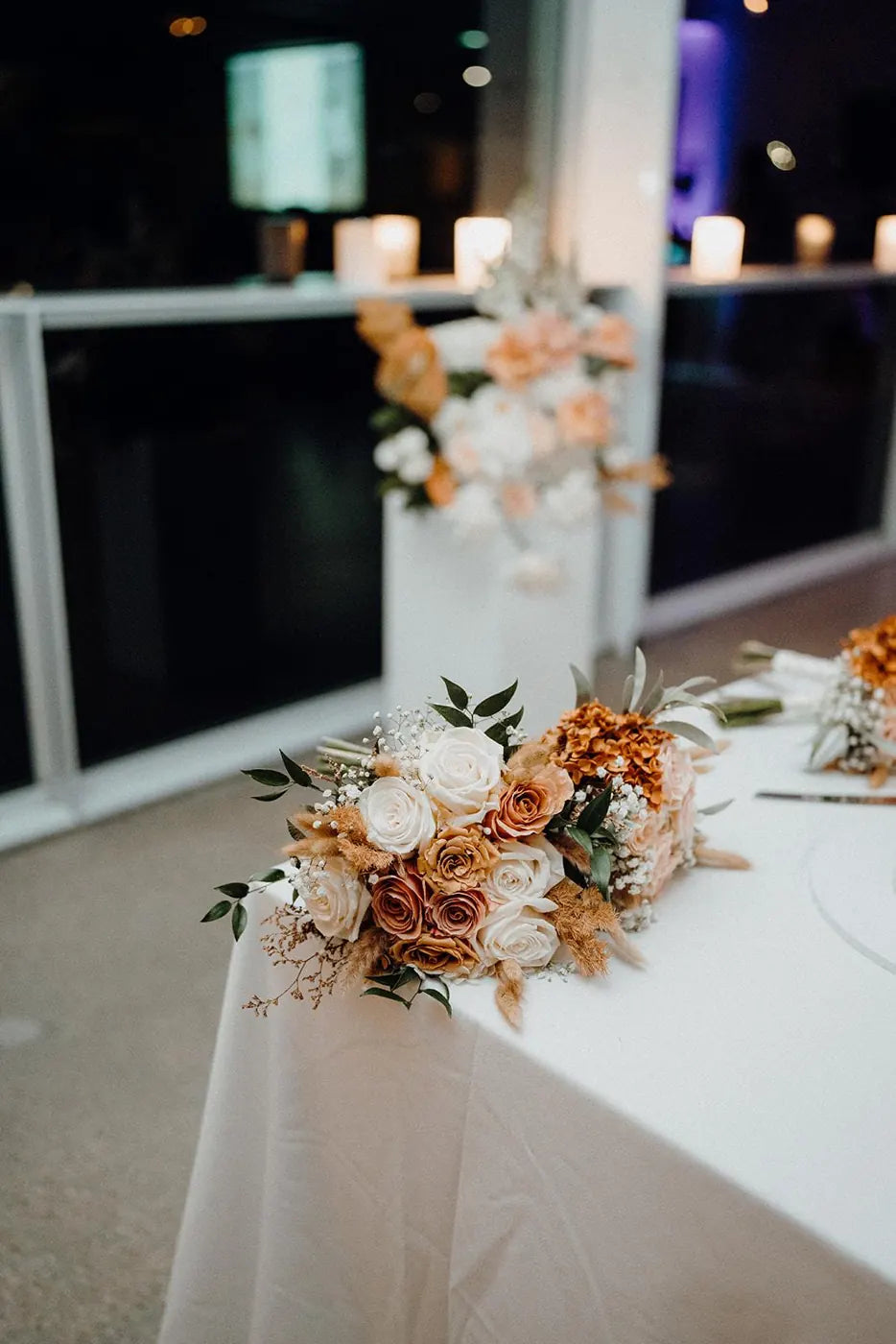 Bridal table floral runner of peach and ivory roses with dried grasses at a Sydney wedding reception