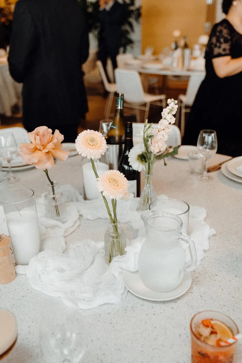 Wedding guest table flowers with apricot roses and gerberas in glass bud vases, Sydney reception styling
